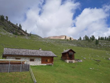 İtalya 'nın bulutlu bir yaz gününde İtalya' nın Alp Dağları 'ndaki San Vigilio di Marebbe köyündeki Tipik Orman ve Taş Evleri ve Yeşil Çayırlar.