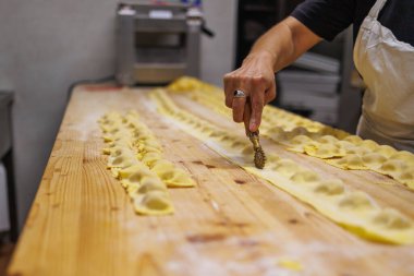 Uzun tahta bir masa üzerinde İtalyan Doldurulmuş Tortelli hazırlanıyor..