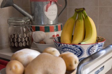 Mutfaktaki el boyalı seramik çömlek kasesinin içinde olgunlaşmış sarı muzlar..