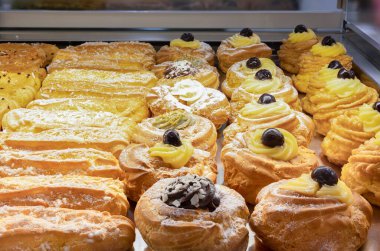 Çikolatalı, kremalı ve meyveli çeşitli hamur işleri bir pastanede sergileniyor..