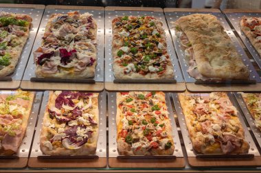 İki raf taze pişmiş pizza ve çeşitli malzemeler..