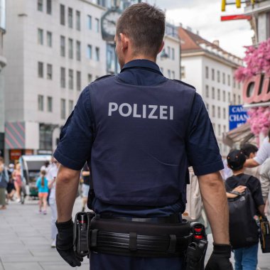 Viyana, Avusturya - 3 Temmuz 2024: Devriye gezen polis memuru şehir caddesinde yürürken görüldü.