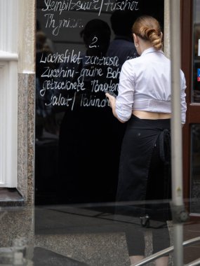 Vienna, Austria - july 3 2024: Waiter Writing the Menu of the Day on the Restaurant's Exterior Blackboard.