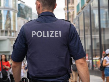 Viyana, Avusturya - 3 Temmuz 2024: Devriye gezen polis memuru şehir caddesinde yürürken görüldü.