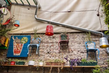 Colorful Chairs Hanging on the Wall and Other Objects inside Ruins Bars in Budapest, creativity and art with Discarded Objects - Hungary. clipart