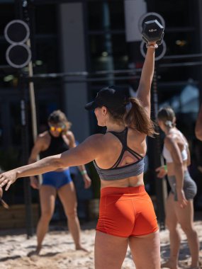 Sahilde antrenman yapan bir grup sporcu, Kumda Kuklayı Kaldıran Kadın.