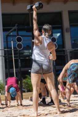 Sahilde antrenman yapan bir grup sporcu, Kumda Kuklayı Kaldıran Kadın.