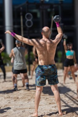 Sahilde antrenman yapan bir grup sporcu, Kumda Kuklayı Kaldıran Adam.