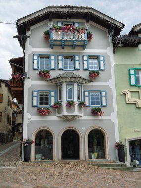 Çiçekli balkonlu geleneksel Alp Binası Mavi Panjurlu, Moena - İtalya.