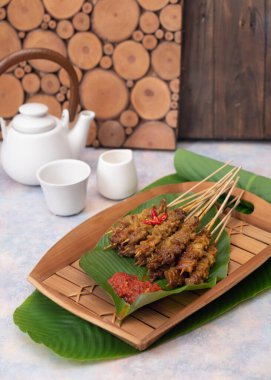 Sate usus or chickens intestines satay. traditional Indonesian street food. On banana leaf and traditional bamboo plate. Selective Focus clipart