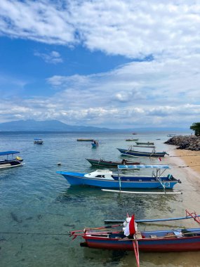 Kuzey Sulawesi, Endonezya 'nın Mando Körfezi kıyılarında berrak mavi gökyüzünde seyreden bir teknenin uzak mesafesinde.