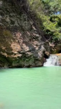 Tomohon, Güney Sulawesi dağlarındaki yeşilliklerle çevrili buharlaşan doğal kaplıcalara akan suyun sabitlenmiş doğa görüntüsü. Dikey Görünüm