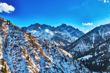panoramic view of snow-capped mountains brightly illuminated by the sun. Shymbulak mountain resort, Almaty, Kazakhstan