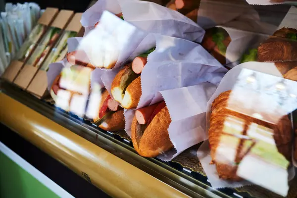 sandwiches, hot dogs and croissants in the refrigerated display case of the diner. Deli counter cooler with take out food