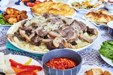 Geleneksel Orta Asya mutfağı beshbarmak ve set masasındaki diğer yemekler.
