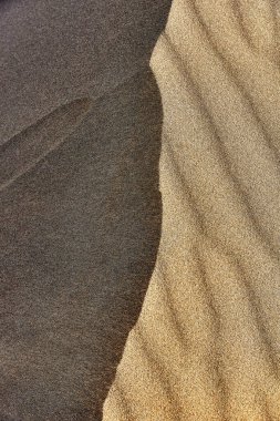 Bir kum tepeciğinin yüzeyindeki dalgaların soyut dokusu