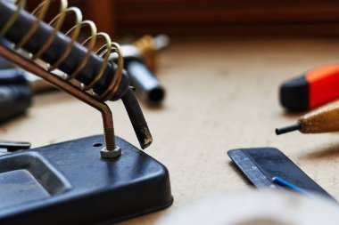 soldering iron in a spiral holder on a stand selective focus with blurred background