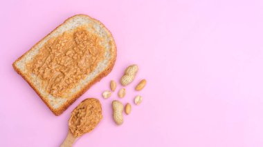 Whole wheat bread and peanut butter on a pink background.