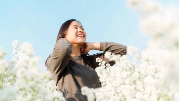Asian woman stands among a white margaret flower.