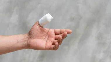 A thumb of men is injured on a gray background.