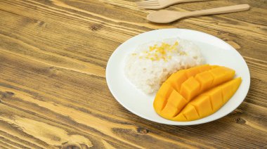 Sticky rice and ripe mango (Thai dessert) on a wooden table.