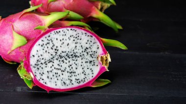 Fresh dragon fruit on a black wooden table.