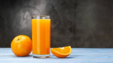 Mavi ahşap bir masada taze portakal suyu..