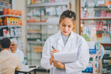 Pharmacist checking Checks Inventory of Medicine, Drugs, Vitamins with tablet and checking patient's prescription in modern pharmacy.