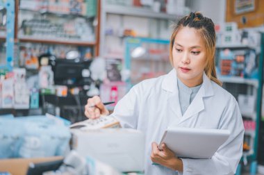 Pharmacist checking Checks Inventory of Medicine, Drugs, Vitamins with tablet and checking patient's prescription in modern pharmacy.