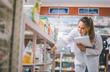 Pharmacist checking Checks Inventory of Medicine, Drugs, Vitamins with tablet and checking patient's prescription in modern pharmacy.