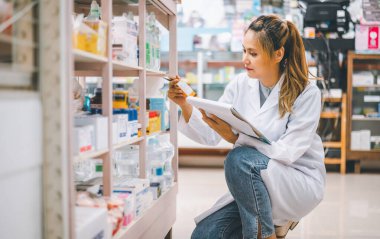 Pharmacist checking Checks Inventory of Medicine, Drugs, Vitamins with tablet and checking patient's prescription in modern pharmacy.