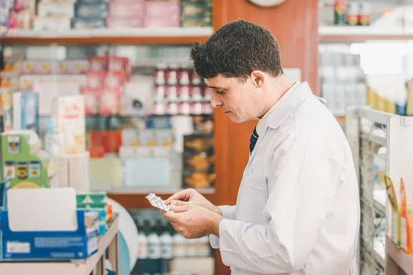 Pharmacist checking Checks Inventory of Medicine, Drugs, Vitamins and prescription medication checks in modern pharmacy.