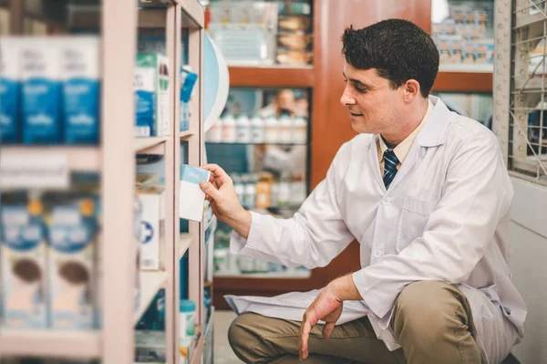 Pharmacist checking Checks Inventory of Medicine, Drugs, Vitamins and prescription medication checks in modern pharmacy.