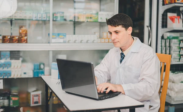 Male pharmacist checking, analyzing or Checks Inventory of Medicine, Drugs, Vitamins and checking prescription drugs for patients in modern pharmacy