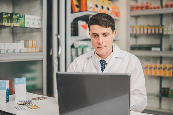 Male pharmacist checking, analyzing or Checks Inventory of Medicine, Drugs, Vitamins and checking prescription drugs for patients in modern pharmacy