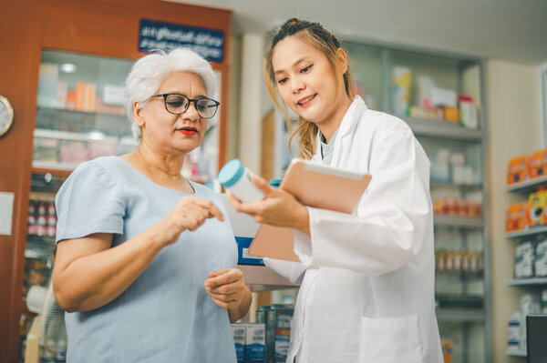 Фармацевт дает советы и советы пациентам, которые приходят покупать лекарства, лекарства, витамины, в соответствии с рецептами в современных аптеках.