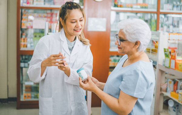 Фармацевт дает советы и советы пациентам, которые приходят покупать лекарства, лекарства, витамины, в соответствии с рецептами в современных аптеках.