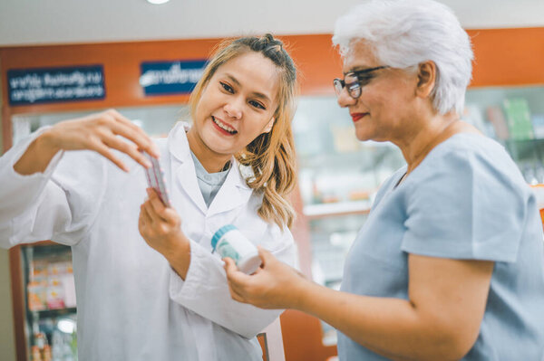 Фармацевт дает советы и советы пациентам, которые приходят покупать лекарства, лекарства, витамины, в соответствии с рецептами в современных аптеках.