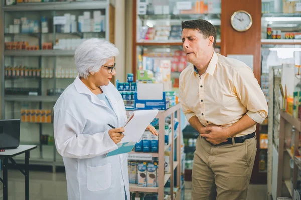 pharmacist is asking about a patient\'s condition in order to prescribe medication according to the patient\'s symptoms who come for prescription consultation in a modern pharmacy.
