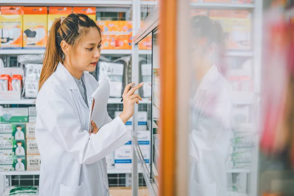 Pharmacist checking Checks Inventory of Medicine, Drugs, Vitamins with tablet and checking patient\'s prescription in modern pharmacy.