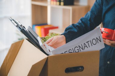 Yeni bir iş aramak, kovulmak ya da işveren tarafından işten atılmak için ofisten çıkmadan önce ofis malzemelerini ve kişisel eşyalarını karton kutulara koyan kadın şirket çalışanı..