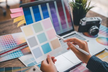 Graphic designer architects who work with laptops and color comparison tables for design work.	