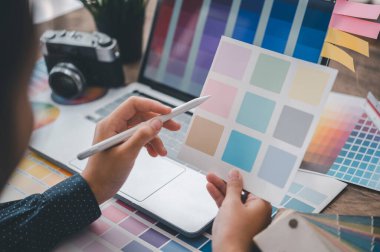 Graphic designer architects who work with laptops and color comparison tables for design work.	