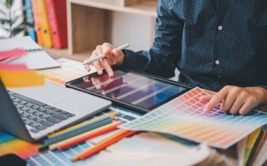 Graphic designer architects who work with laptops and color comparison tables for design work.	