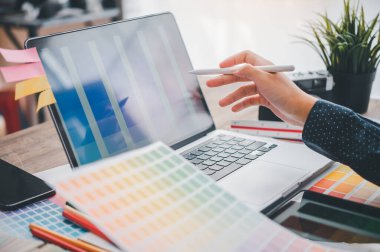 Graphic designer architects who work with laptops and color comparison tables for design work.	