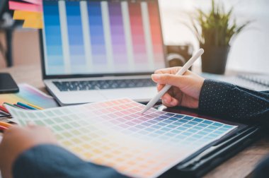 Graphic designer architects who work with laptops and color comparison tables for design work.	