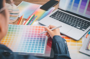 Graphic designer architects who work with laptops and color comparison tables for design work.	