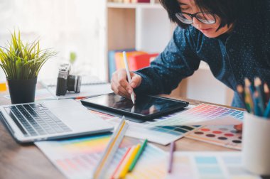 Graphic designer architects who work with laptops and color comparison tables for design work.	