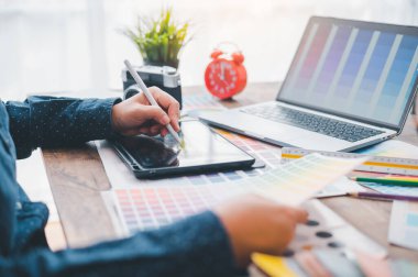 Graphic designer architects who work with laptops and color comparison tables for design work.	