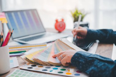 Graphic designer architects who work with laptops and color comparison tables for design work.	